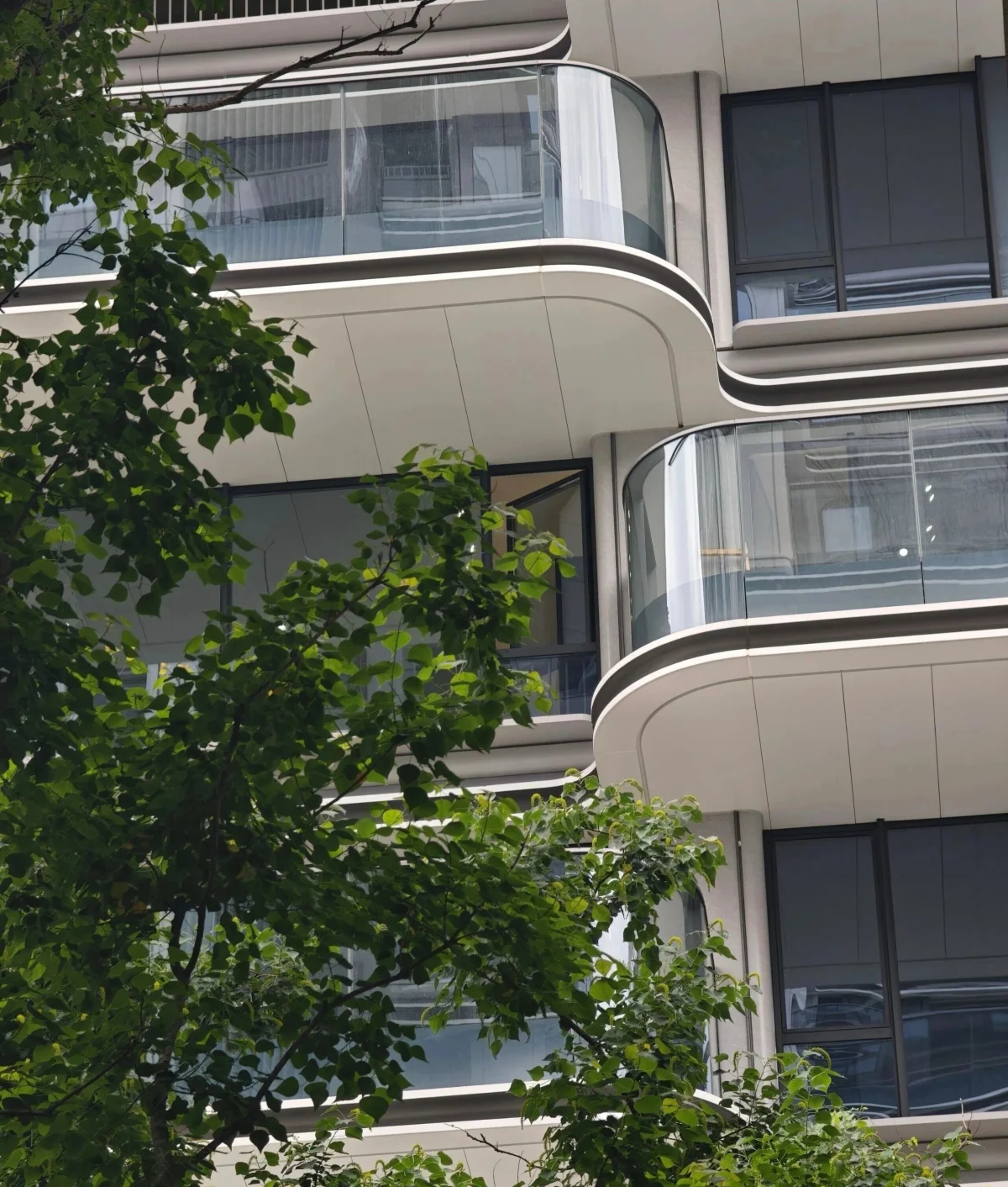 Separate residential facade with rounded balcony edges, pale soffits and glazed balustrades.