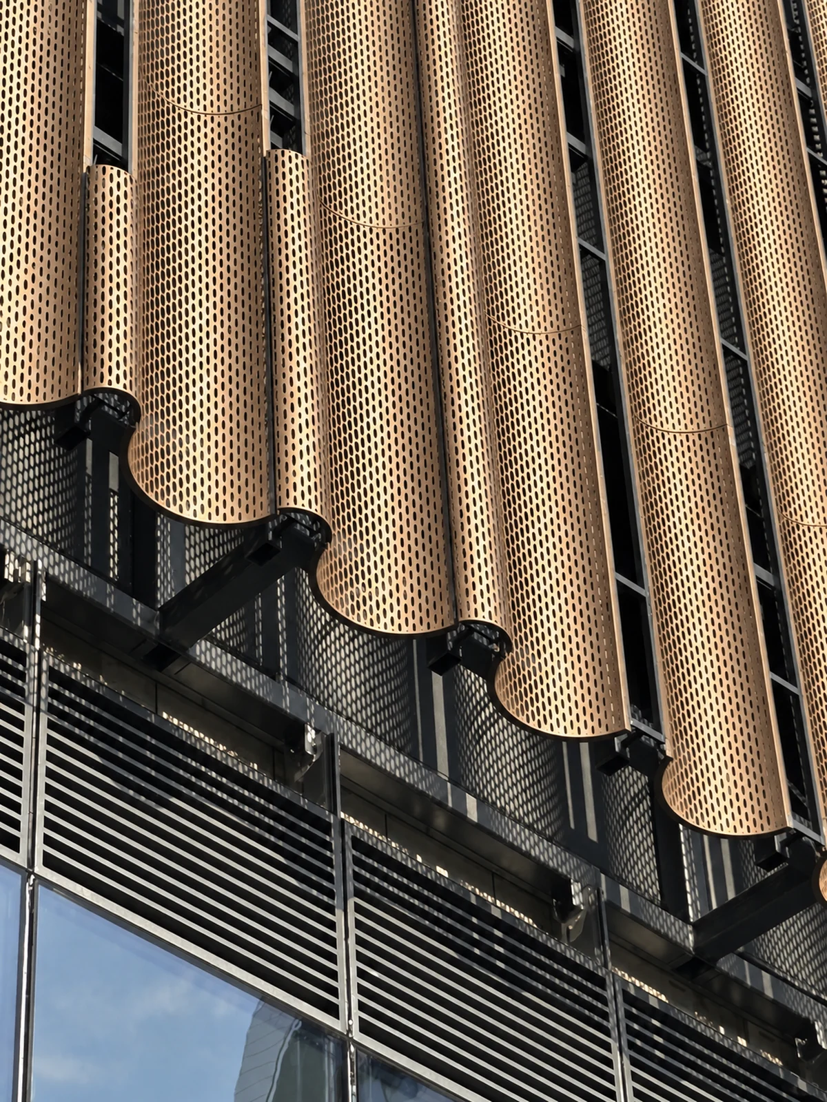 A different architectural project: rounded bronze-toned perforated fins on dark framing.