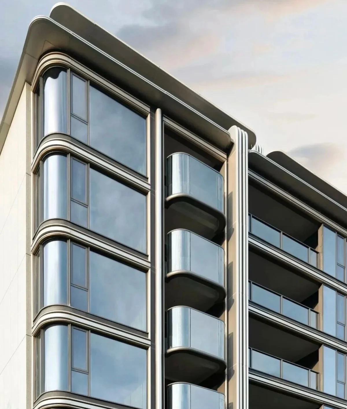 A residential facade with rounded projecting balconies, curved glazing and layered silver-toned edges.