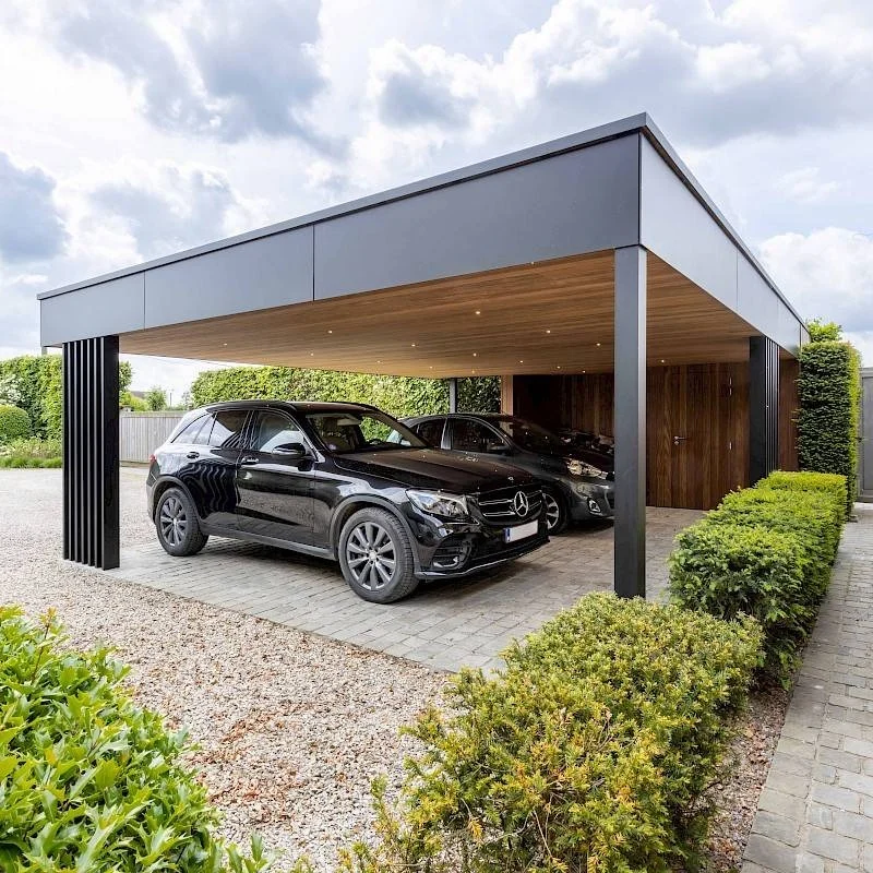 Two cars beneath a flat-roof carport with a timber soffit, dark columns and a planted approach.